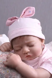 Close-up of sleeping reborn baby doll with detailed skin texture and pink rabbit ear hat