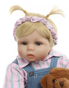 Gros plan d'une poupée reborn faite main avec tresses et petit ours en peluche