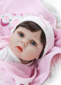 Gros plan d'une poupée réaliste avec yeux bleus et bonnet en tricot rose à pois