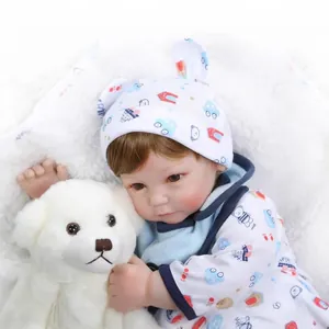 Realistic reborn baby doll boy in white cartoon outfit holding a plush white bear