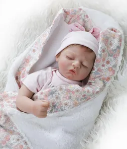 Close-up of a lifelike sleeping baby doll in a pink outfit with a floral swaddle blanket