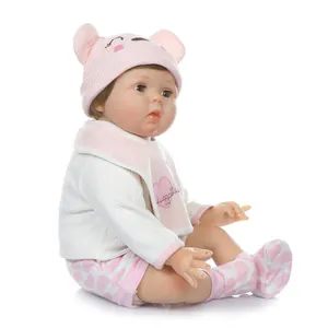 Realistic reborn baby doll in pink knit outfit with bear ear hat and huggable bib