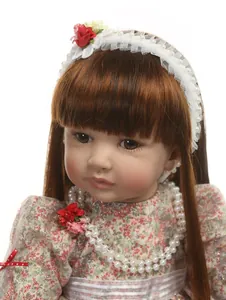 Gros plan d'une poupée reborn avec de longs cheveux bruns et une robe à fleurs