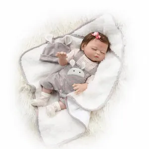 Realistic reborn baby doll in pink rabbit outfit sleeping on plush white blanket