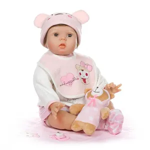 Lifelike reborn baby doll in pink knit hat with bear toy and pacifier on white background