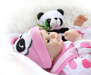 Primer plano de una muñeca reborn realista con traje de panda rosa y un pequeño panda de peluche