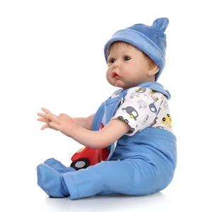 Bambola reborn realistica con berretto blu e tutina con auto dei cartoni su sfondo bianco