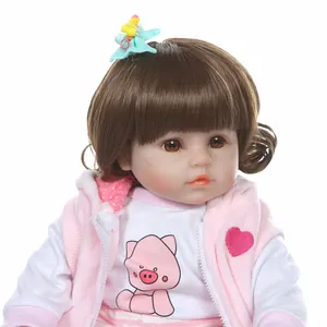 Lifelike reborn baby doll with long brown hair wearing pink cartoon fleece vest