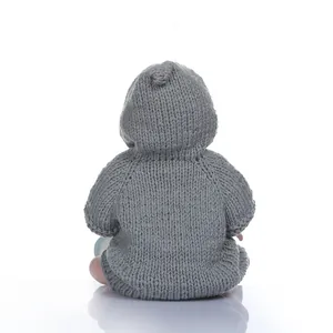 Back view of realistic baby doll wearing a grey chunky knit hoodie on white background