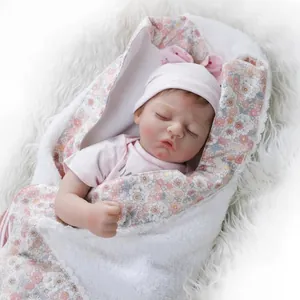 Reborn baby doll sleeping in pink outfit and floral fleece blanket on white rug