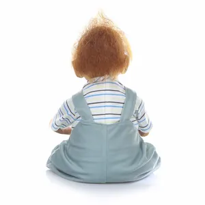 Rear view of lifelike baby orangutan doll in blue striped t-shirt and denim overalls