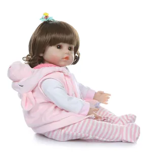 Realistic reborn toddler doll with long brown hair and pink pig-themed hoodie outfit