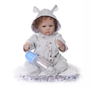 Realistic reborn baby doll in grey giraffe hoodie with bottle on plush white mat