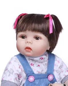 Detailed close-up of a lifelike baby doll with brown pigtails and blue overalls