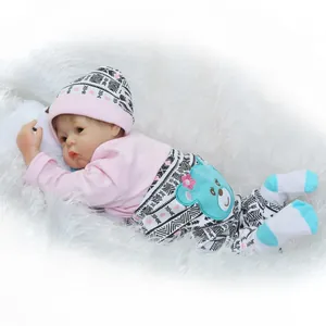Realistic reborn baby doll in pink and blue outfit on soft white plush background