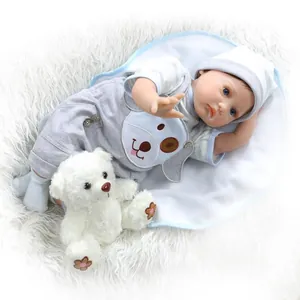 Realistische reborn babypop in blauwe gestreepte outfit met pluche beer op wit tapijt