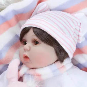 Realistic reborn baby doll in pink knit hat and scarf set on a soft striped blanket