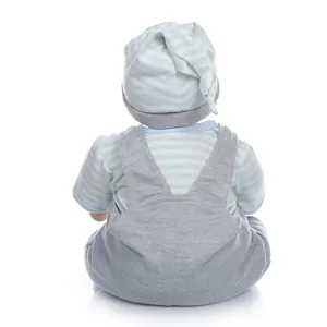 Achteraanzicht van een reborn babypop met blauw gestreepte outfit en grijze tuinbroek op wit