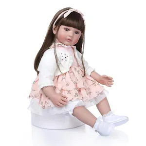 Realistic reborn toddler doll with long brown hair in a floral dress and pink cardigan