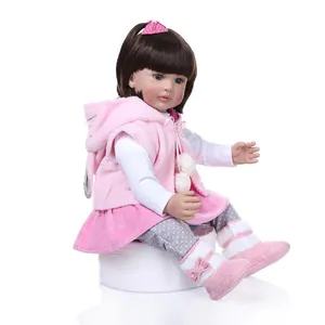 Reborn toddler princess doll with brown hair and pink plush vest on white background
