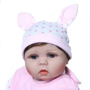 Realistic reborn baby doll in pink polka dot rabbit ear hat and matching bib on white