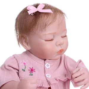 Lifelike reborn baby doll in pink ribbed outfit sleeping peacefully on white background