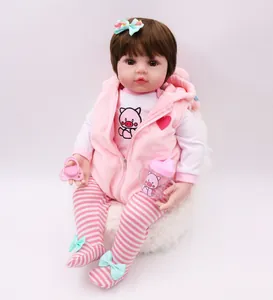 Close-up of a realistic reborn baby doll with brown hair, pink vest, and matching accessories