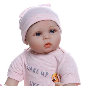 Poupée bébé réaliste aux yeux bleus portant une tenue rose et un bonnet tricoté