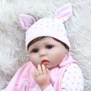 Realistic reborn baby doll in pink rabbit outfit on soft white plush background