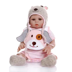 Realistic newborn baby doll in pink striped outfit and grey bear hat on white background