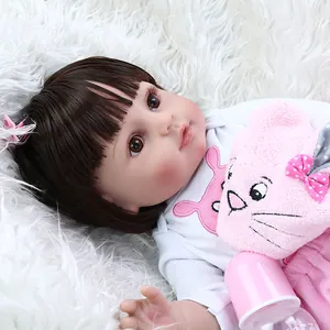 Lifelike reborn baby doll with brown hair and white shirt on soft plush rug