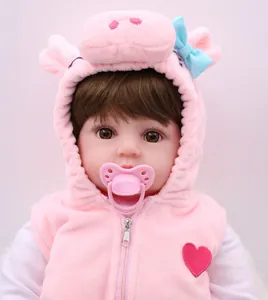 Close-up of a reborn baby doll wearing a pink pig themed plush hoodie with a pacifier