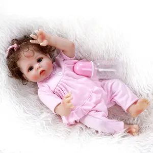 Detailed close-up of a lifelike reborn baby doll in pink outfit on plush background