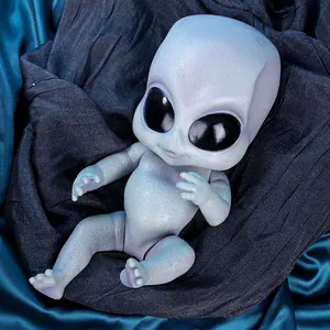 Poupée bébé extraterrestre réaliste avec peau texturée et yeux noirs sur satin bleu