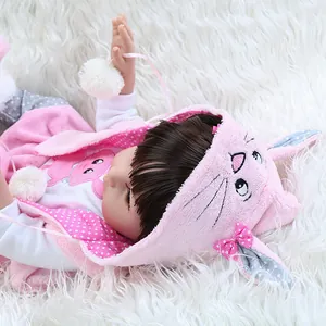 Realistic reborn baby doll in pink bunny outfit with long hair on white faux fur rug