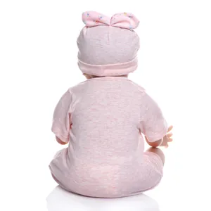 Rückansicht einer lebensechten Reborn-Puppe in rosa geblümtem Outfit und Schleifenhut