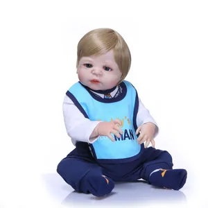 Realistic reborn baby doll with blonde hair, blue eyes and light blue bib on white background