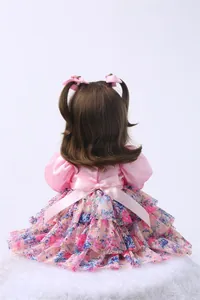 Détails de la poupée 60cm montrant le haut en satin rose et la jupe fleurie en mesh