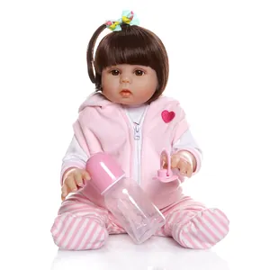 Lifelike reborn baby doll with brown hair, pink hooded vest and stripe pants on white back