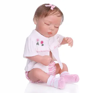 Close-up of sleeping reborn baby doll with pink bow and floral embroidery details