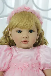 Dettaglio di bambola reborn con capelli biondi ricci e occhi azzurri con decoro rosa