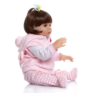 Realistic 47cm newborn baby doll with brown hair and pink hooded outfit on white background