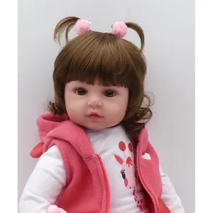 Realistic reborn baby doll with curly brown hair, pink fleece vest, and giraffe print top