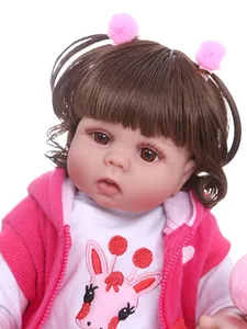 Close-up of lifelike reborn baby doll featuring rooted brown curls and pink hair clips