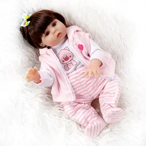Realistic reborn baby doll in pink hoodie and pig pattern outfit on plush white carpet