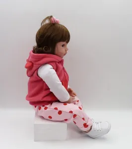 Detailed side view of realistic baby doll in pink fleece vest and polka dot trousers