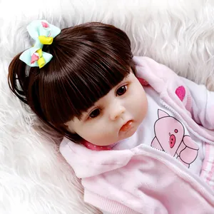 NPK lifelike reborn baby doll with long brown hair and pink hoodie on plush carpet