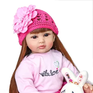 Realistic reborn toddler doll with long brown hair in pink knit hat and rabbit toy