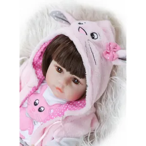 Close-up of realistic reborn baby doll in pink rabbit themed hoodie with cute ears