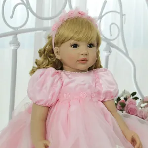Bambola reborn principessa 60cm con capelli biondi e vestito floreale rosa sul letto